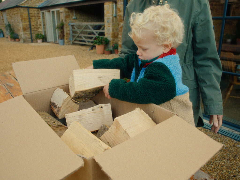 A child helping pack a box of ash logs at Leys Farm