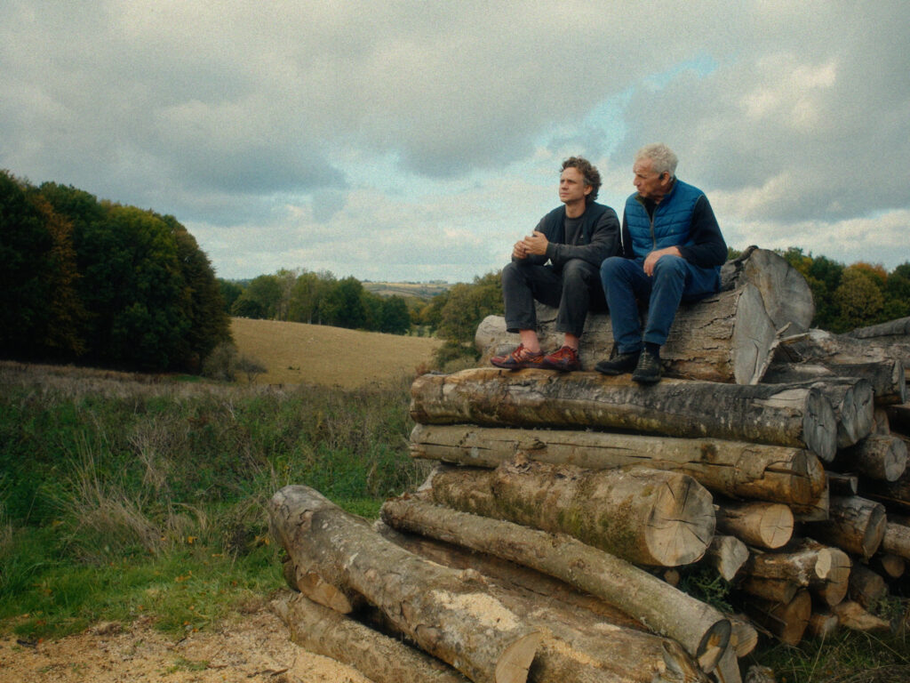 Jonathan and Will sitting on stacked timber at Leys Farm
